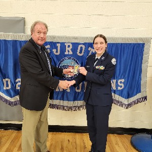 ROTC student and instructor shake hands while holding award